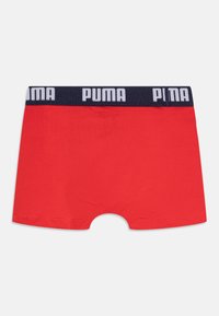 Boxer rouge avec une ceinture élastique bleu marine portant le texte blanc "PUMA". Tissu lisse et coupe ajustée, avec une ouverture pour la jambe.