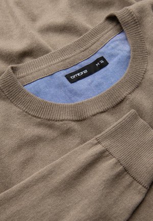 Ljusbrun tröja med ribbad rundhals och mudd, med en kontrasterande blå innerribb. Mjuk textur, enkel design, inga synliga mönster.