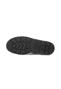 Semelle noire d'une botte avec un motif de crampons profond comprenant des formes en zigzag et en flèche, fabriquée en caoutchouc pour l'adhérence et la durabilité.
