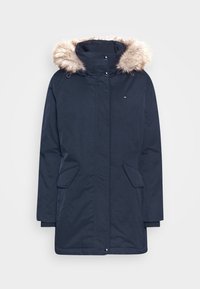 Námořnická bunda s umělým kožíškem na kapuci, zapínáním na zip a patentky, dvěma předními kapsami a elastickými manžetami. Měkká textura, minimalistický design.