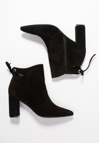 Botines de ante negros con punta afilada, tacón cuadrado, cremallera lateral y un detalle de cordones en la parte posterior. Textura suave con diseño minimalista.