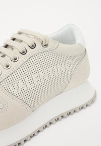 Beige suede sneakers met mesh-details, witte accenten, ronde neus en vetersluiting. Beschikt over een logo en een getextureerde rubberen zool.