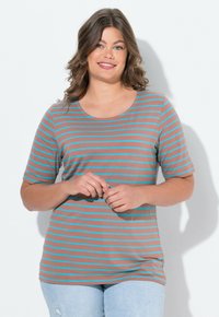 Camiseta a rayas en marrón con líneas turquesa, de manga corta, con cuello redondo y una textura suave. Combinada con jeans de color azul claro.