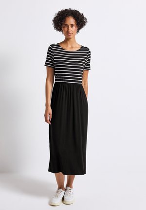 Striped black and white short-sleeve dress with a gathered black skirt, made of soft fabric. Worn with white sneakers.