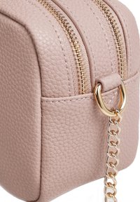 Pochette in pelle texturizzata rosa con design arrotondato, dettagli con cerniera dorata e un'accenno di catena dorata per il trasporto.