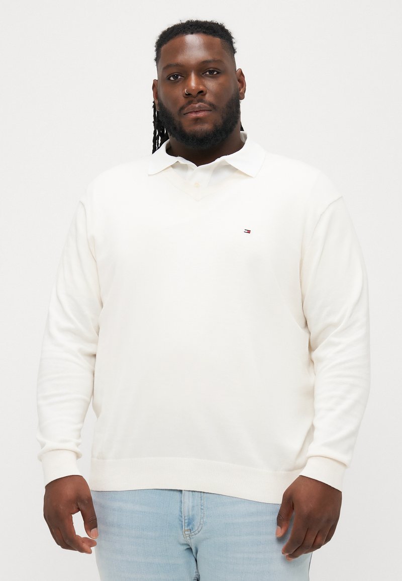 Krém színű pulóver V-nyakkal és hosszú ujjakkal. Kis logó található a mellkason, bordázott mandzsettákkal készült, puha anyagból.