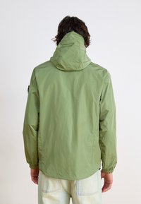 Light green hooded jacket with a lightweight texture, elastic cuffs, and a flat seam design, viewed from the back.