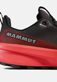 Czarno-czerwony but trekkingowy z teksturowaną cholewką, z wyraźnym logo, metką Gore-Tex oraz grubą, kontrastującą podeszwą zapewniającą przyczepność.