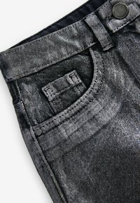 Sorte denim jeans med en tekstureret, mønstret overflade, en forlommer og metalliske hardware-detaljer.