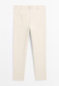 Pantalons en coton beige avec une texture lisse, dotés de deux poches arrière et d'une coupe ajustée sans aucune quincaillerie ni motifs visibles.