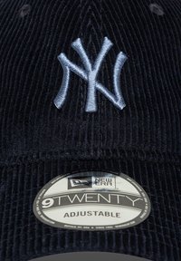 Tengerészkék kordbársony baseball sapka hímzett világoskék NY logóval. Állítható pánttal rendelkezik, és egy "9TWENTY" felirattal ellátott kör alakú címke található rajta.