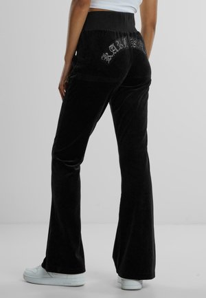 Schwarze Samt-Glockenhosen mit einem festen Bund, ausgestattet mit Strassdetails auf den hinteren Taschen und einer glatten Textur.