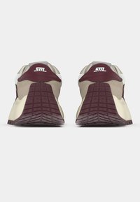Chaussures de sport marron et bordeaux avec semelles texturées, accents blancs, et un design de talon arrondi avec un logo à l'arrière.