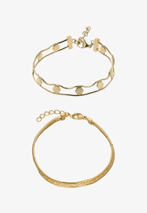 Twee gouden armbanden: een met hexagonale accenten op een golvende ketting, en de andere is glad en flexibel met een sluiting en een verlengketting.