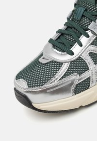 Nike-sneaker med övre i grön mesh och silverdetaljer, med en texturerad design, rund tå och svart gummisula.