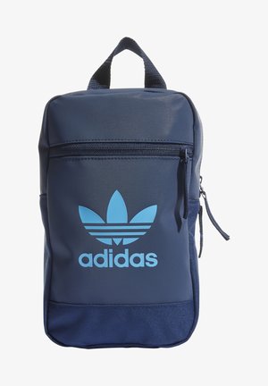 Bolsa Adidas azul marino con bolsillo delantero con cremallera y logo trefoil azul claro y texto, además de un asa superior tejida.
