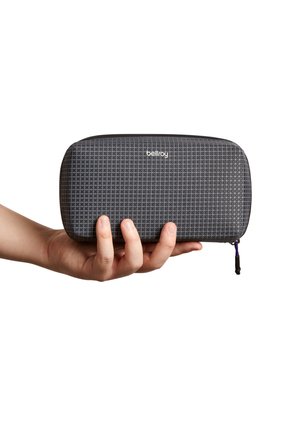 Trousse à crayons grise avec un motif en grille, fabriquée en matériau durable, dotée d'un curseur de fermeture éclair violet et d'un logo discret à l'avant.