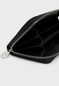 Portafoglio nero con zip, realizzato in tessuto testurizzato, dotato di molteplici scomparti per carte e di una cerniera in tono argento con un'etichetta circolare.