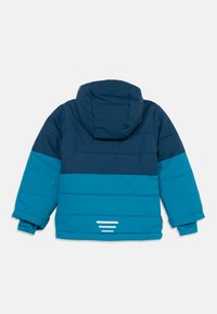 Giacca imbottita per bambini con cappuccio, blocchi di colore in blu scuro e blu brillante, mostrata di schiena con strisce riflettenti vicino all'orlo.