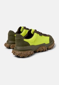 Grüne und leuchtend gelbe Sneakers mit strukturierten Sohlen, die Schnürsenkel und gepolsterte Zungen zeigen, positioniert, um die Details an Ferse und Seite hervorzuheben.