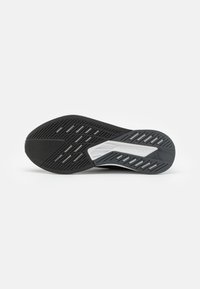 Suola di scarpa atletica nera con superficie in gomma testurizzata, caratterizzata da un'intersuola Lightstrike grigia e un design di scanalature verticali e ritagli.