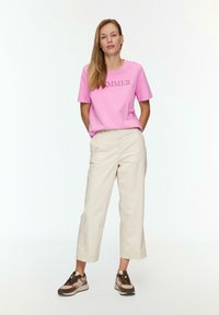 Rosa Baumwoll-T-Shirt mit dem Text "SUMMER", beigefarbene, cropped Hosen und braune sowie beigefarbene Sneaker. Glatte Texturen und lässige Passform.