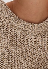 Sweter dziewiarski z okrągłym dekoltem, wykonany z beżowego i kremowego włóczki. Posiada teksturowany wzór z różnymi rozmiarami ściegów.
