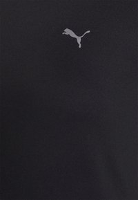 Camiseta deportiva negra hecha de tela suave que presenta un pequeño logo Puma en gris claro en el pecho.