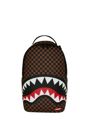 Zaino con motivo a scacchiera marrone e nero con una grande bocca stilizzata con denti bianchi e gengive rosse sulla tasca anteriore.