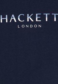 Námořnická modrá bavlněná tričko s výrazným bílým textem "HACKETT LONDON" s elegantním designem a hladkou texturou.