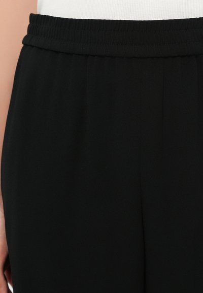 Schwarze Hose mit elastischem Bund, aus glattem, leichtem Stoff und mit dezenten Falten an den Seiten für Flexibilität und Komfort.