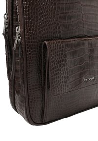 Barna krokodilmintás bőr táska elülső zsebfedővel és dupla cipzáras záródással. Simas textúra fémes kiegészítőkkel.