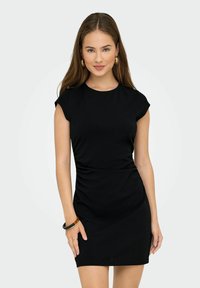 Robe noire ajustée avec des manches courtes, décolleté rond et détails froncés sur les côtés, fabriquée dans un tissu lisse et extensible.