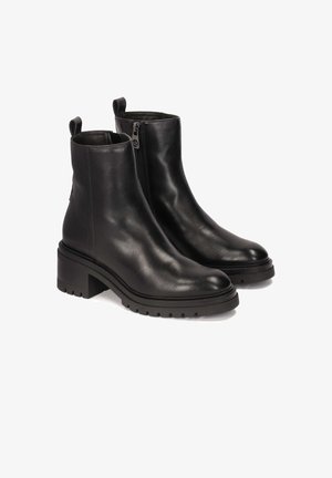 Par af sorte læder ankelstøvler med sidelukning, kraftige hæle, løftelinser og slidbanesåler på hvid baggrund.