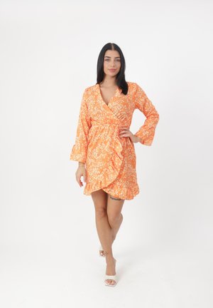 Robe portefeuille en tissu orange à fleurs, avec un ourlet volanté, des manches longues et un décolleté en V. Fabriquée en tissu léger. Agrémentée de petites fleurs blanches.