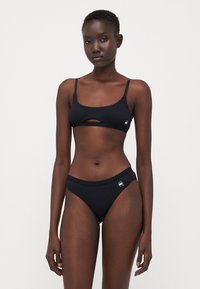 Svart bikini-sett med en kort topp med sentral utskjæring, justerbare stropper og matchende høytaljede bukser, laget av glatt stoff.