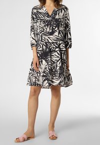 Blommönstrad klänning i marinblått och krämfärgat, med v-ringning och trekvartslånga ärmar. Kombineras med rosa slidesandaler.