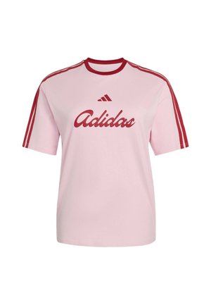 Jasnoróżowa koszulka Adidas z czerwonym kołnierzem, trzema czerwonymi paskami na rękawach i czerwonym logo oraz napisem Adidas z przodu.
