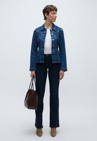 Τζιν μπουφάν με εφαρμοστή γραμμή, σκούρο μπλε χρώμα, ασημένια κουμπιά και μακριά μανίκια, συνδυασμένο με σκούρα τζιν καμπάνα και ταμπά μποτάκια μέχρι τον αστράγαλο. Καφέ τσάντα ώμου.