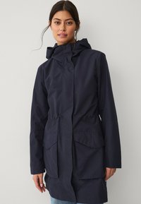 Marineblauwe waterdichte jas met een capuchon, elastische taille en twee grote voorzakken. Heeft een gladde textuur en een minimalistisch ontwerp.