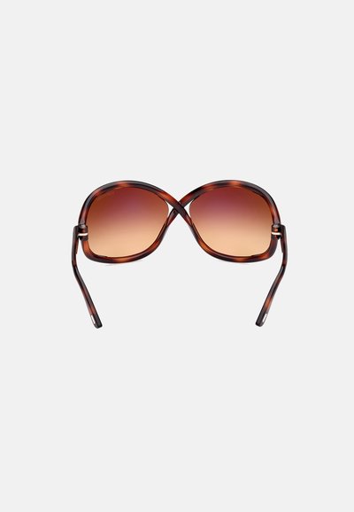 Schildpatt-Sonnenbrille mit übergroßer ovaler Form, getönten braunen Gläsern und dünnen, geschwungenen Bügeln mit dezenten goldenen Akzenten.