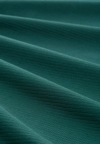 Gestruktureerde teal stof met een golvend patroon, met een subtiele ribbelstructuur. Het materiaal lijkt zacht en flexibel te zijn.
