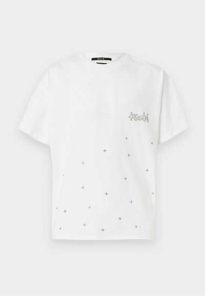 Balta kokvilnas T-krekls ar īsām piedurknēm, ar logotipu uz krūtīm un sīku metālu krustu izkaisītu rakstu.