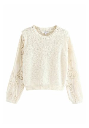 Pull en maille crème avec corps sans manches texturé et longues manches en dentelle transparente avec motifs circulaires complexes.