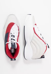 Białe i czerwone tenisówki z teksturowaną skórzaną cholewką, granatowymi akcentami, wyściełanym kołnierzem i okrągłymi sznurowadłami. Posiadają wyprofilowane boczne wzory.