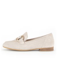 Light beige suede loafer with a flat heel, featuring a decorative gold hardware buckle on the vamp. Smooth texture and simple design.