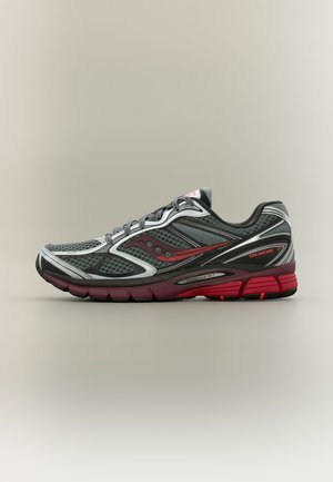 Chaussure de course Saucony Guide 7 grise et rouge avec empeigne en mesh et semelle amortie, vue de côté sur un fond uni.