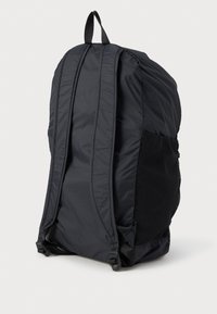 Zaino in nylon nero con spallacci imbottiti, una tasca laterale in rete testurizzata e una maniglia superiore per un facile trasporto.