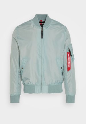 Lysblå bomberjakke med en blank finish, ribbede manchetter og kant, to sidelommer og et rødt bånd på ærmet med tekstdetalje.