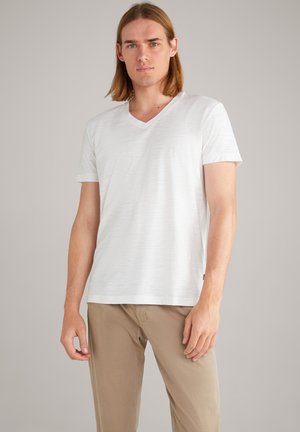 White v-neck t-shirt made from a textured fabric, featuring short sleeves and a relaxed fit. Paired with beige trousers.